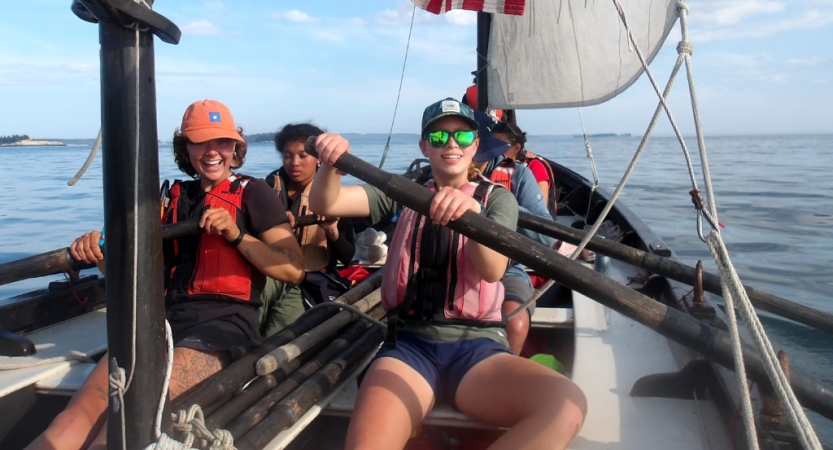 a group of people wearing life jackets use oars to navigate a sailing boat